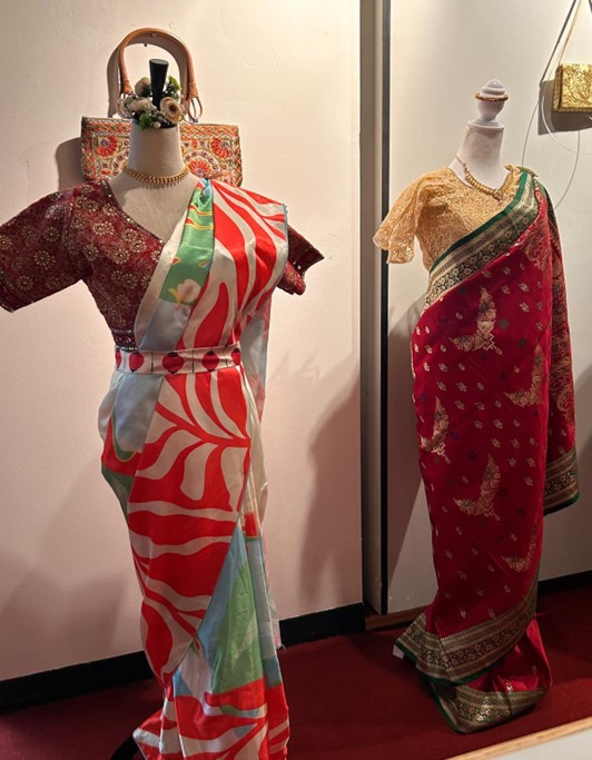 A modern holiday colored saree for wellness, and cancer awareness inspired by late Tomasz Kowalski and designed by Green Fad stands at the entry way besides a vintage Sri Lankan silk saree. PHOTO: International Museum of Sarees (IMAS)